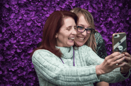 people posing for selfie in front of purple flowers