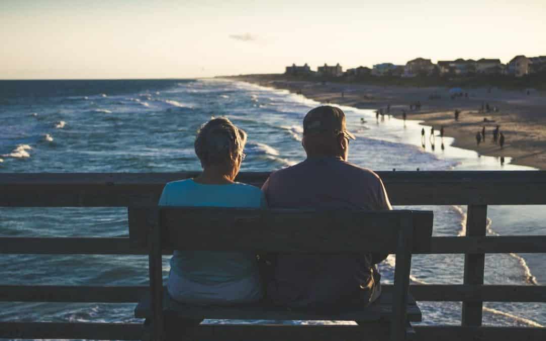 couple sitting on bench looking at the ocean