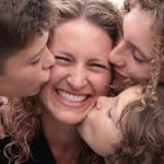 woman with children kissing her face