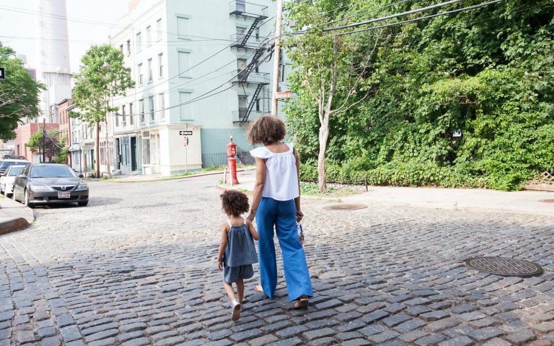 woman in white cap-sleeved shirt and blue pants walking beside girl in gray tank top