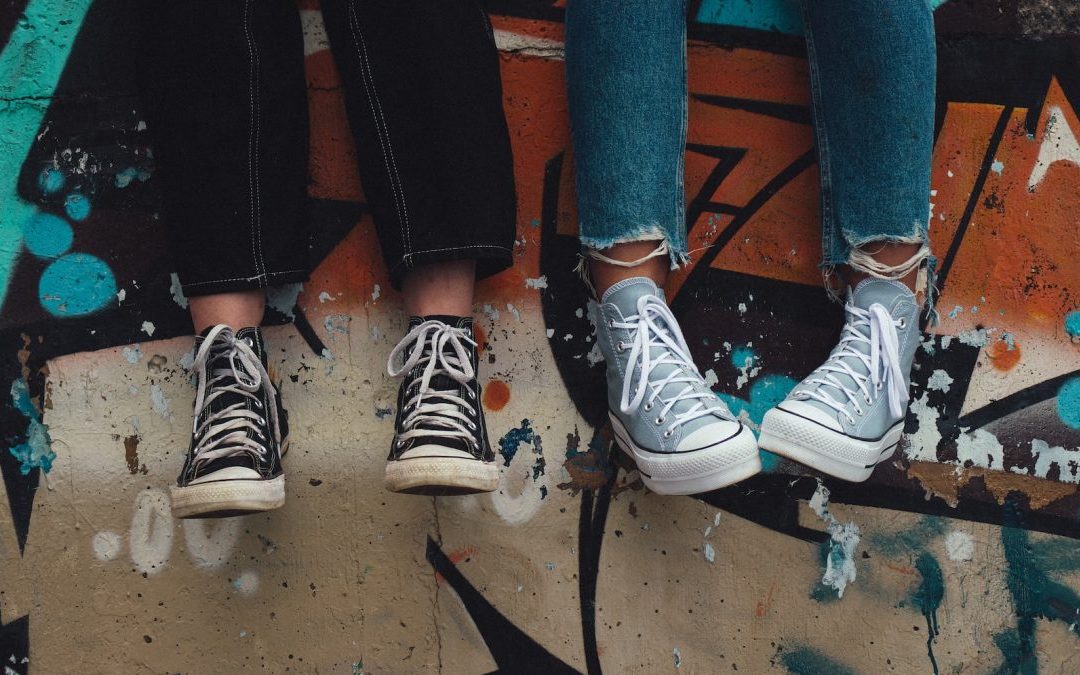 person in blue denim jeans wearing black and white converse all star high top sneakers